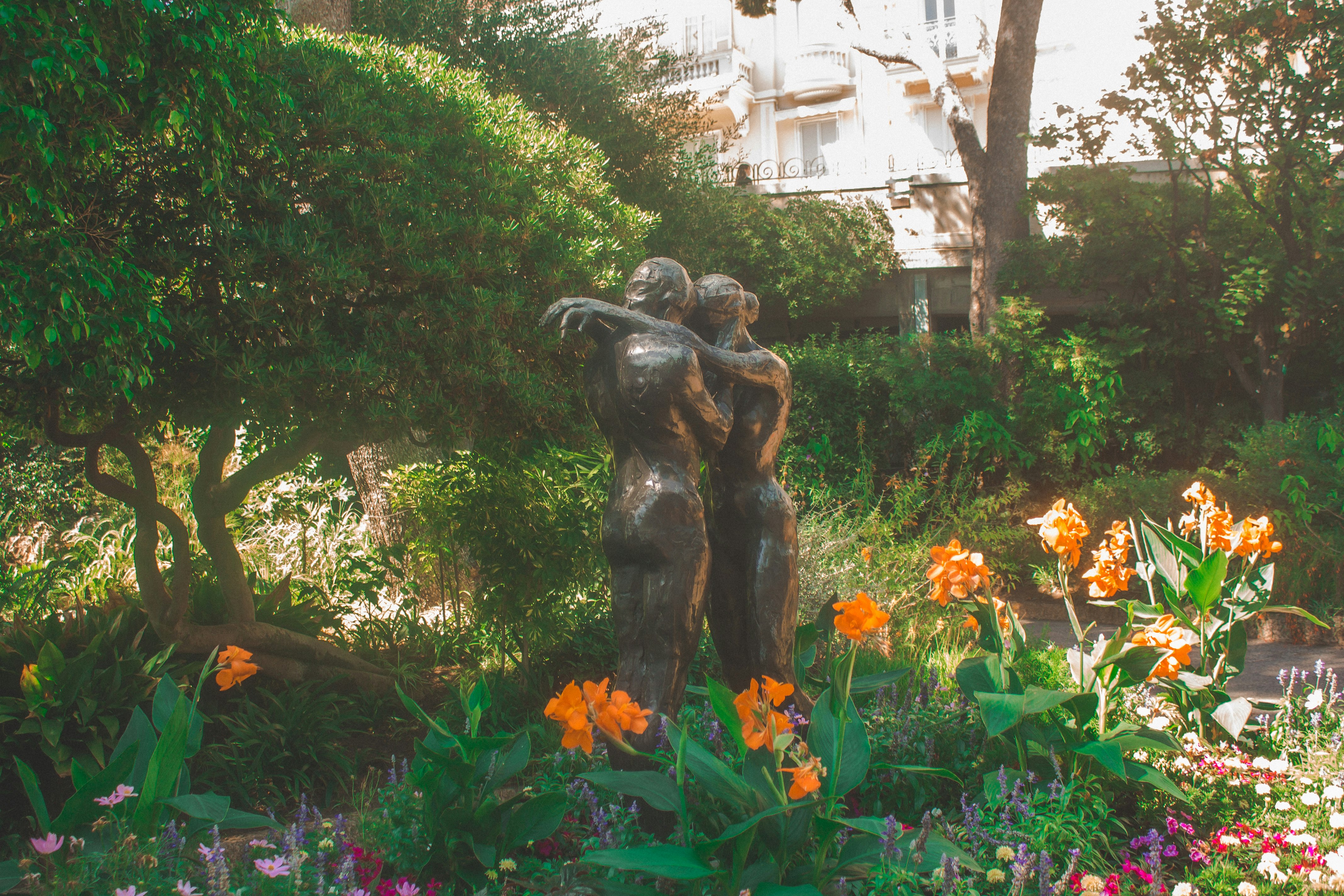 black statue surrounded by green plants and trees during daytime